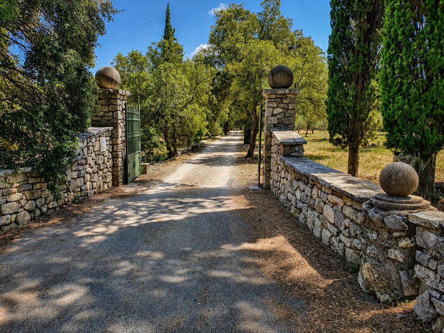Allée privée avec cyprès et mur en pierres